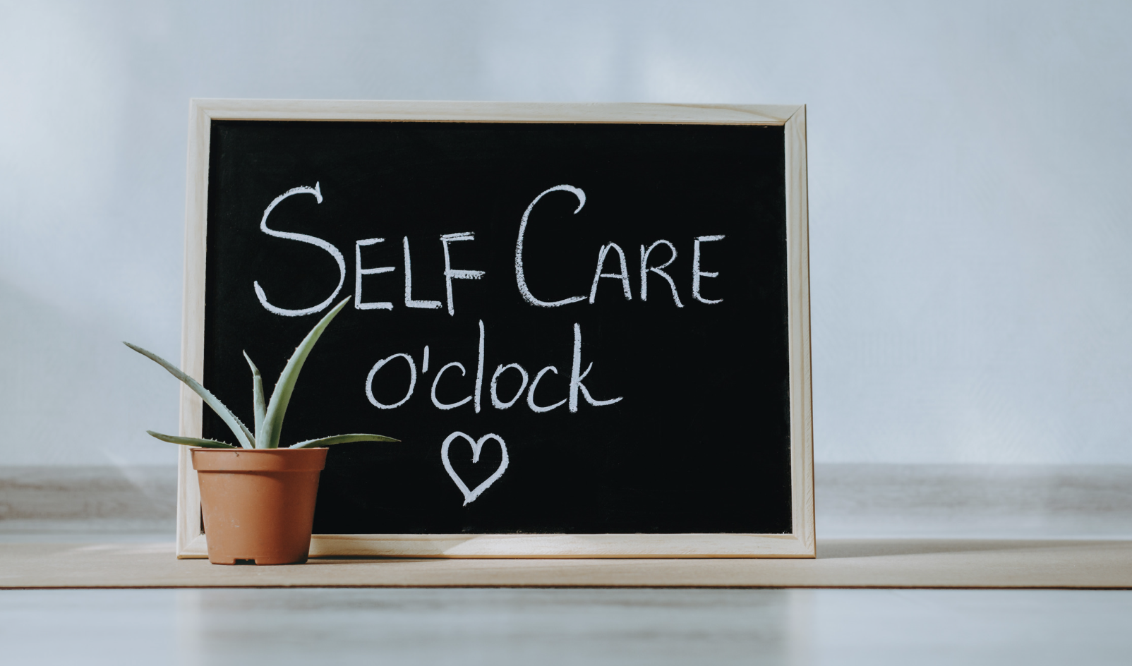 Small chalk board with the message Self Care O'clock written on it.